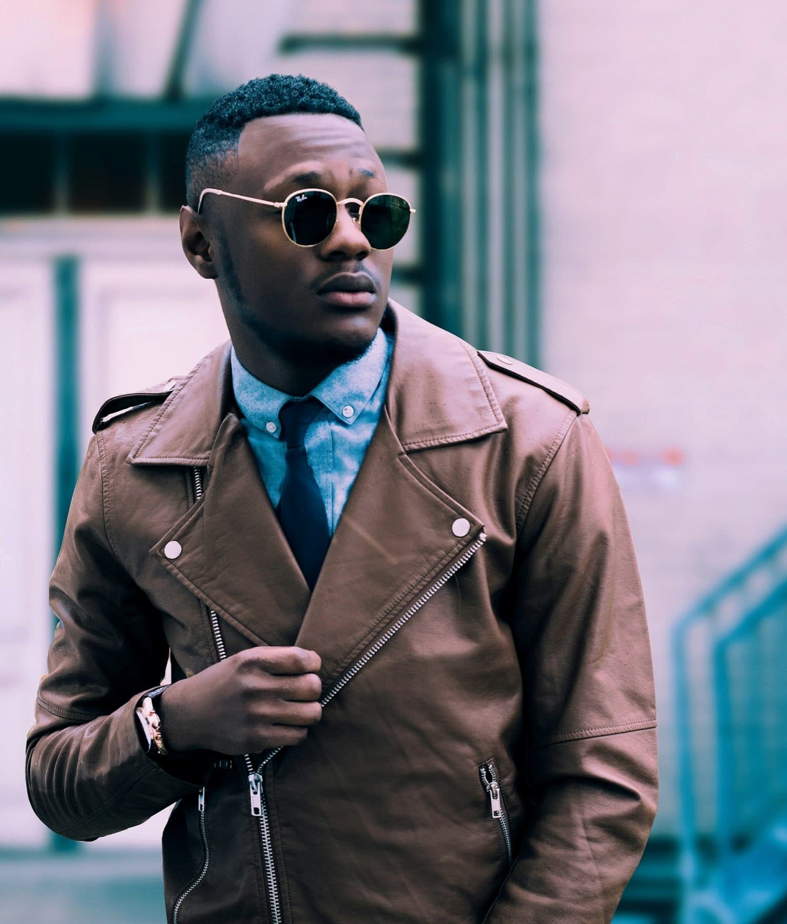 Menswear portrait, leather jacket, gold-rimmed lenses.