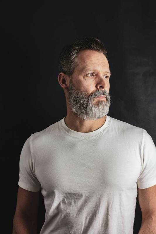 Close portrait, dark studio, hair across one eye.