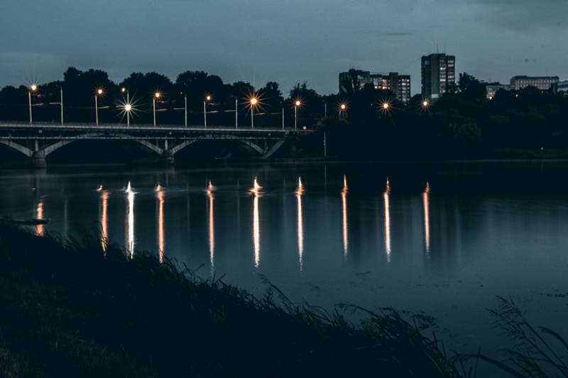 Blue hour waterfront, moon just above the towers.