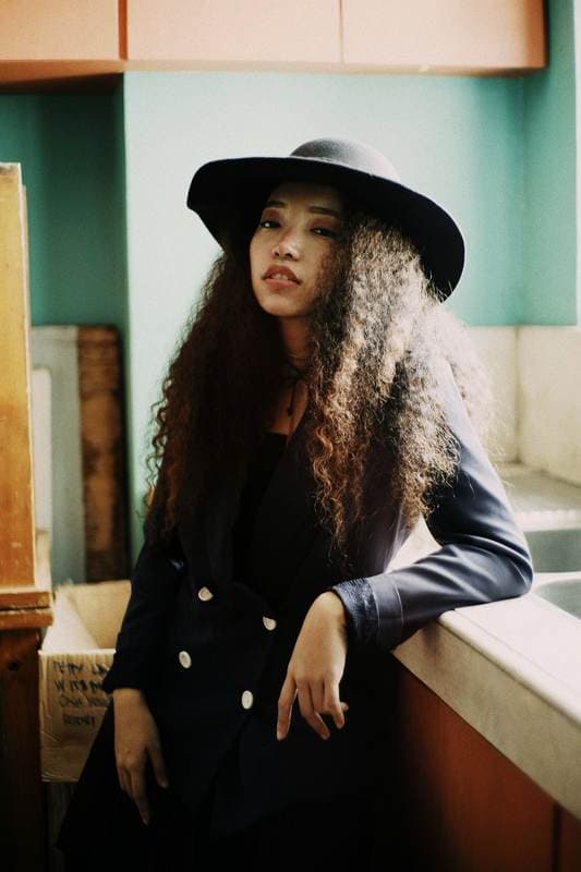 Wide-brim hat and navy jacket in a turquoise interior.