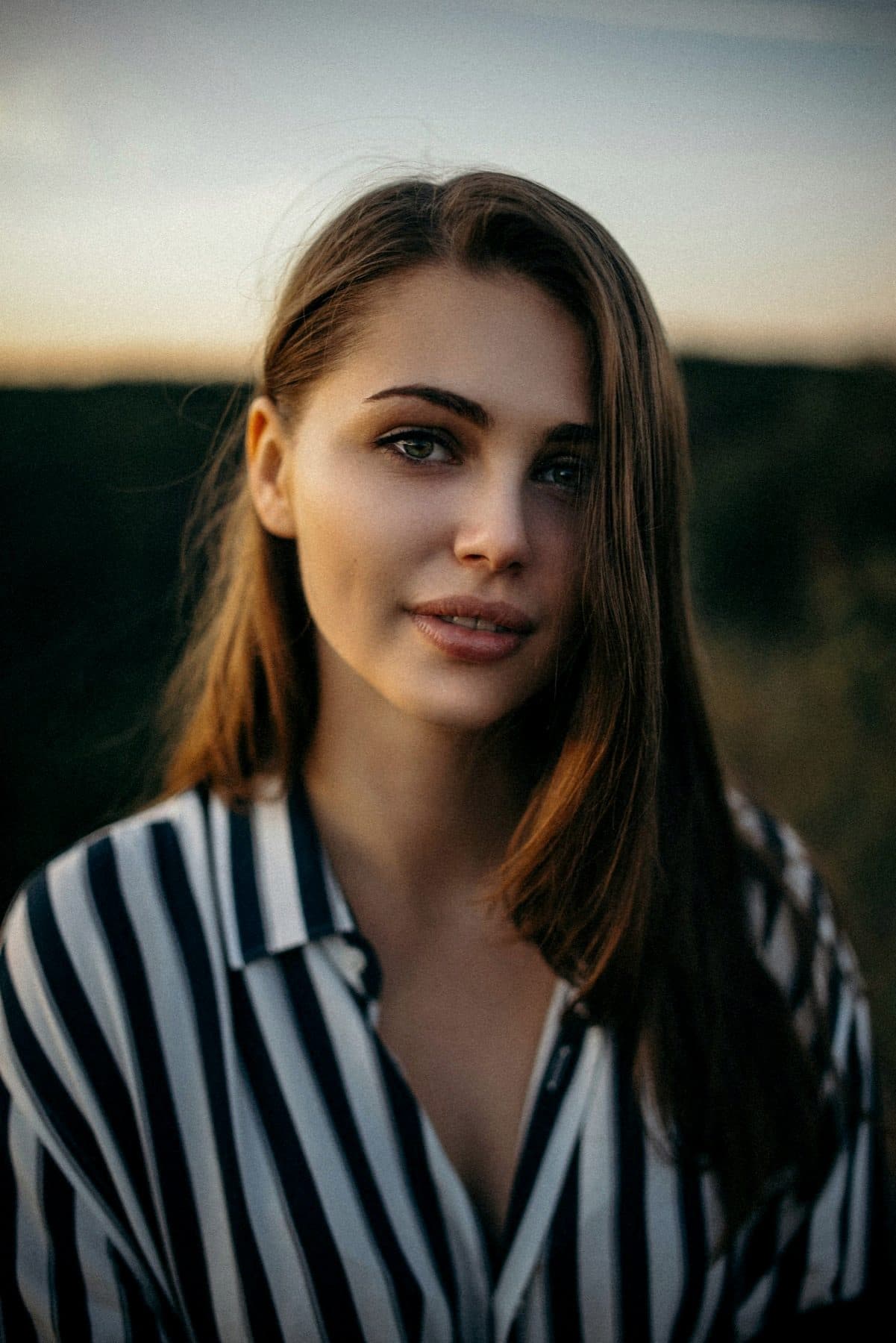 Dusk portrait, striped shirt, eyes held just off camera.