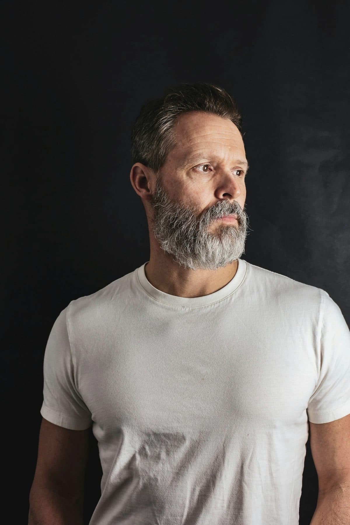 Close portrait, dark studio, hair across one eye.